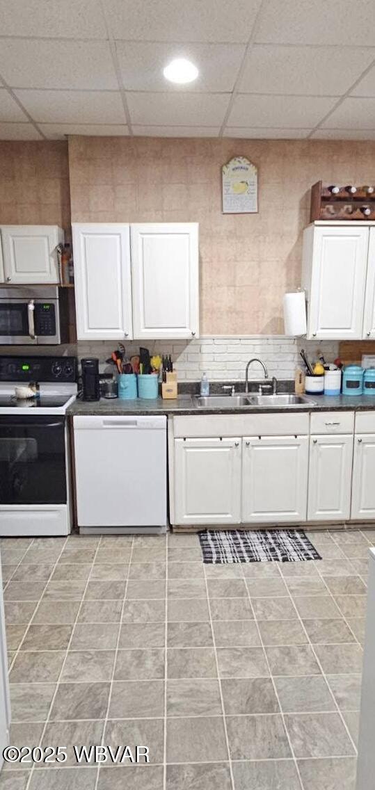 103 Lower Market St, Milton, PA 17847 - kitchen featuring white appliances, a sink, dark countertops, white cabinets, and a paneled ceiling