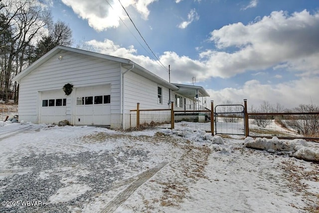 view of snow covered exterior featuring a garage and fence