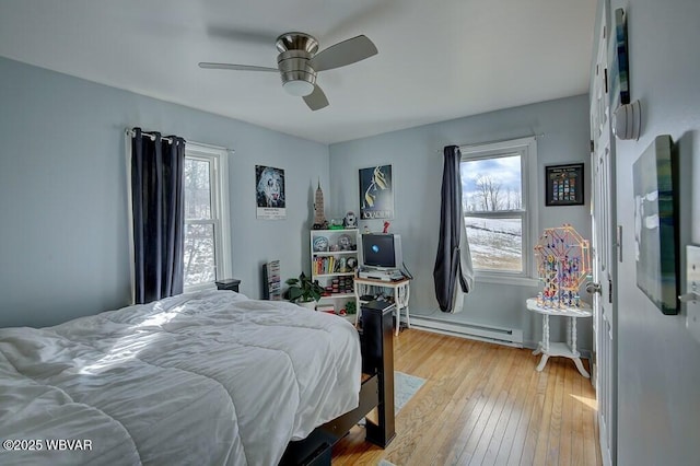 bedroom with ceiling fan, light wood-style flooring, multiple windows, and baseboard heating