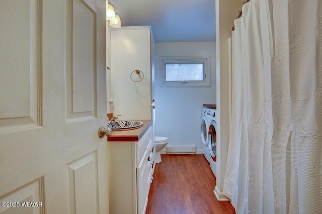 full bath with washer and clothes dryer, toilet, wood finished floors, vanity, and a baseboard heating unit