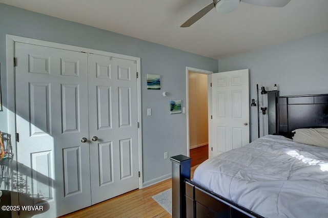 bedroom with baseboards, ceiling fan, a closet, and light wood-style floors