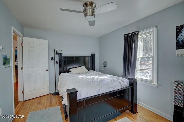 bedroom featuring heating unit, light wood finished floors, ceiling fan, and baseboards