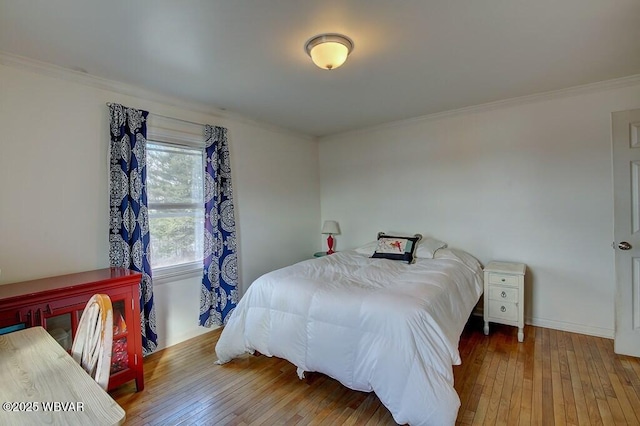 bedroom featuring ornamental molding, wood finished floors, and baseboards