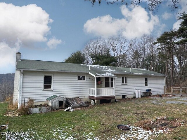 rear view of house featuring a chimney and a lawn