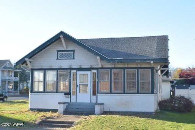 back of property with a sunroom and a lawn