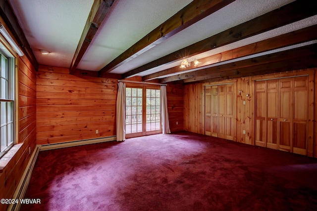 carpeted empty room featuring wood walls, a baseboard heating unit, baseboard heating, and beamed ceiling