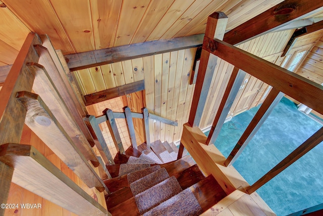 stairs featuring wooden ceiling, vaulted ceiling with beams, and wooden walls