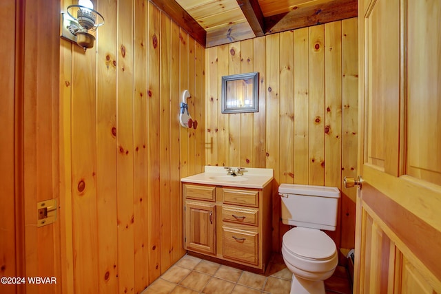 bathroom with tile patterned floors, vanity, toilet, and wooden walls