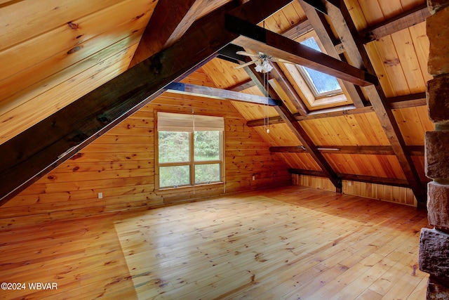 bonus room featuring vaulted ceiling with skylight, wood walls, and hardwood / wood-style floors