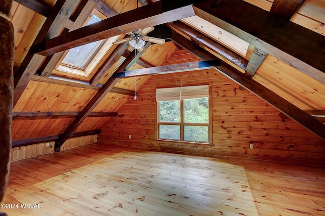 additional living space with lofted ceiling with skylight, wood walls, and hardwood / wood-style floors