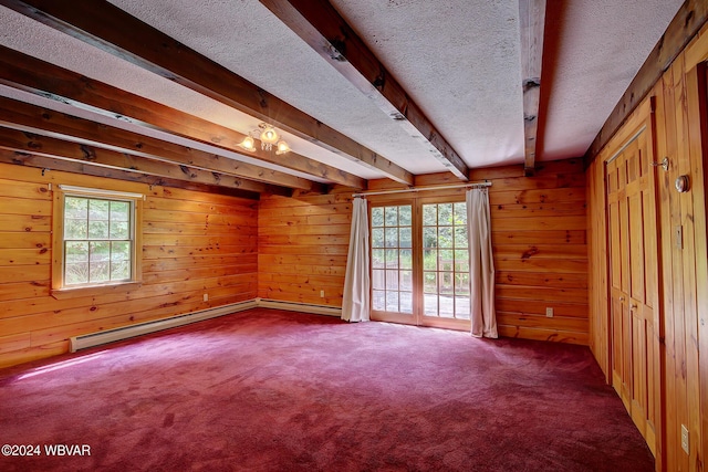 spare room featuring a textured ceiling, a baseboard heating unit, dark carpet, and a wealth of natural light