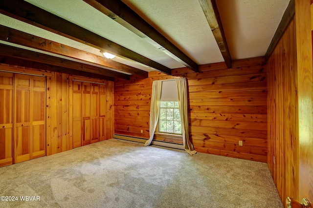 unfurnished room with wooden walls, baseboard heating, beam ceiling, and carpet flooring