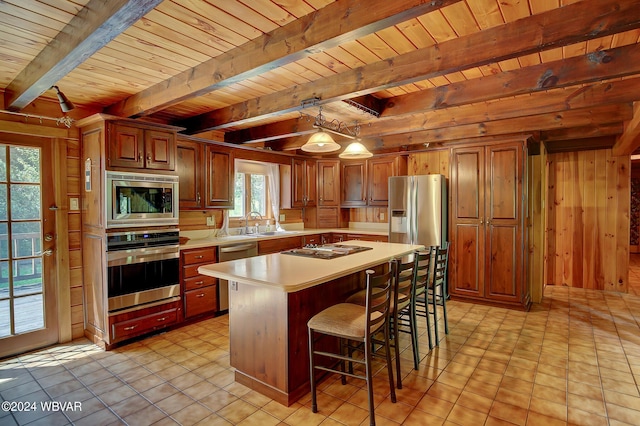 kitchen featuring wooden walls, wooden ceiling, appliances with stainless steel finishes, a breakfast bar area, and light countertops