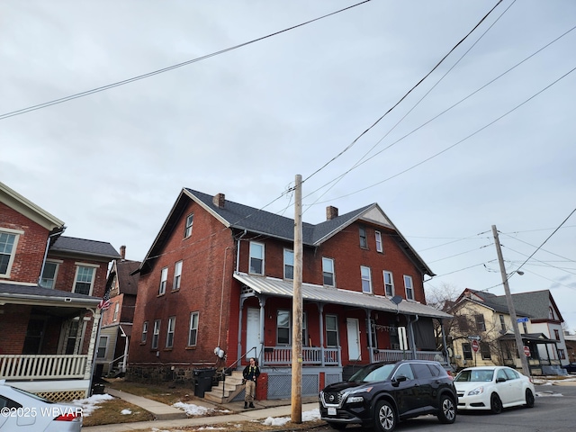 townhome / multi-family property with a porch and brick siding