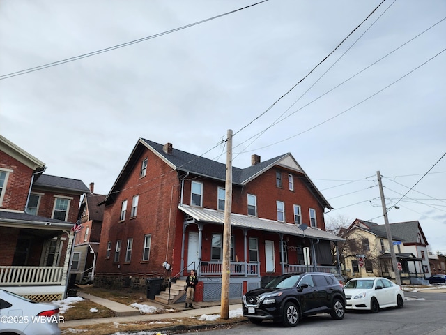 townhome / multi-family property featuring a porch, brick siding, and a chimney