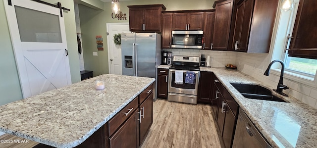 250 Mclaughlin Rd, Milton, PA 17847 - kitchen with appliances with stainless steel finishes, a sink, a barn door, backsplash, and light wood finished floors