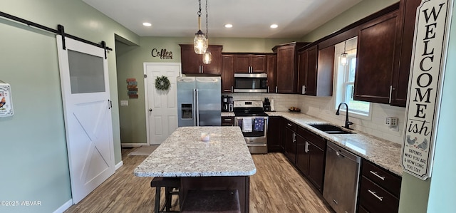 250 Mclaughlin Rd, Milton, PA 17847 - kitchen with stainless steel appliances, a sink, wood finished floors, a barn door, and dark brown cabinetry