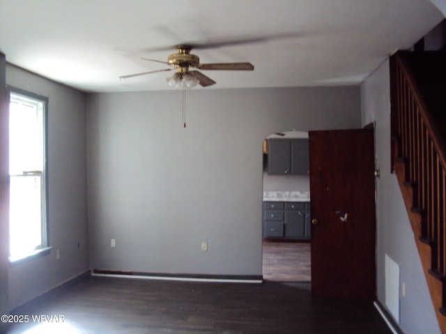 empty room with dark wood-style flooring, ceiling fan, and plenty of natural light