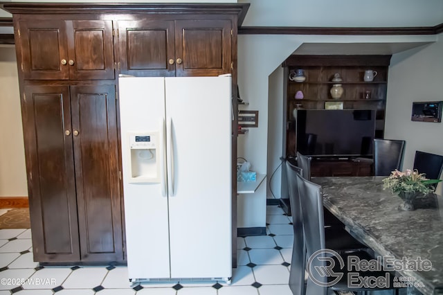 kitchen with dark stone countertops, dark brown cabinets, and white fridge with ice dispenser