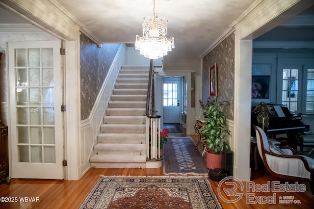 stairway featuring ornamental molding, wood-type flooring, and a chandelier