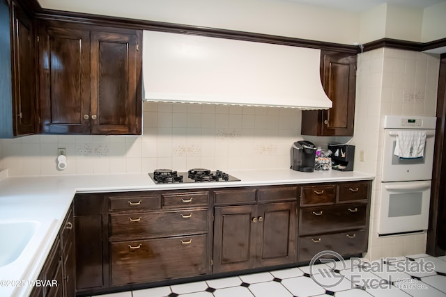 kitchen featuring tasteful backsplash, double oven, dark brown cabinets, and gas cooktop