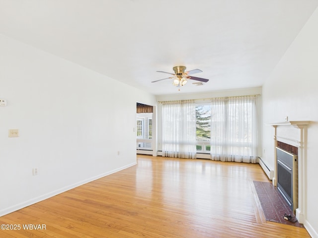 unfurnished living room featuring light wood-type flooring, a glass covered fireplace, a baseboard heating unit, and baseboards