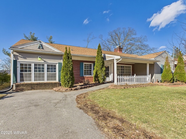 single story home with a front yard, a chimney, aphalt driveway, and brick siding