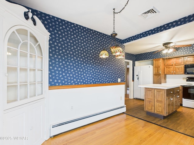 kitchen with a baseboard radiator, white appliances, visible vents, brown cabinetry, and wallpapered walls