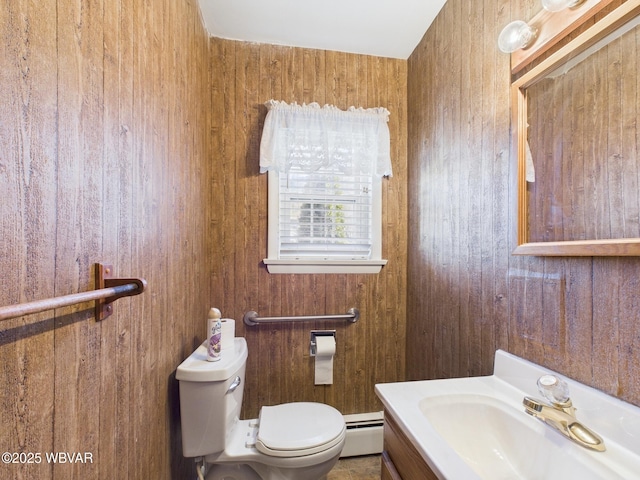 half bath with toilet, wood walls, baseboard heating, and vanity