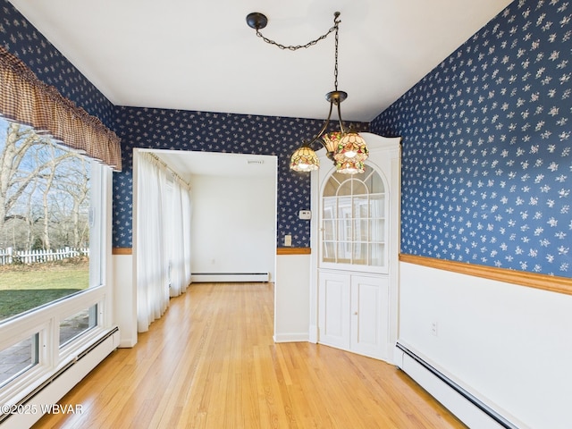 unfurnished dining area with baseboard heating, wood finished floors, and wallpapered walls