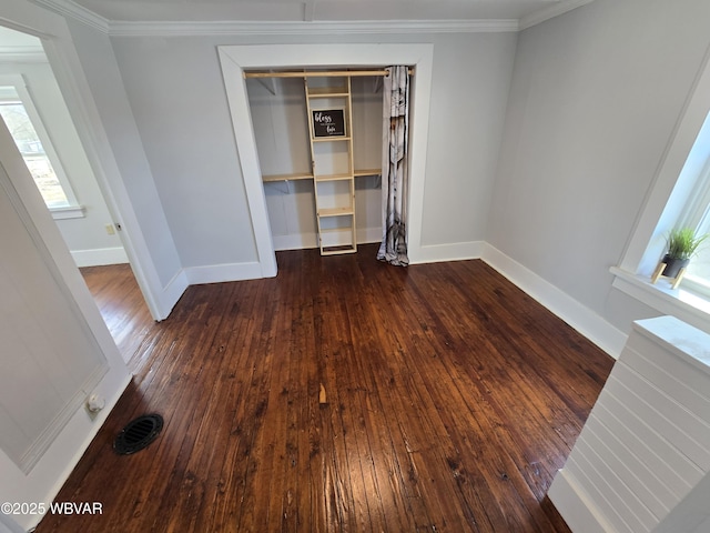 unfurnished bedroom featuring crown molding, dark wood-type flooring, and a closet