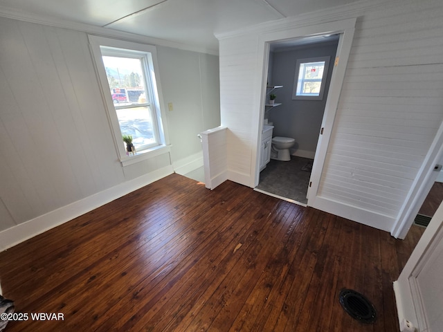 unfurnished bedroom featuring dark hardwood / wood-style flooring, crown molding, and ensuite bathroom