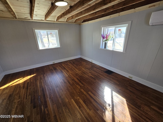 spare room featuring dark wood-type flooring, a wall mounted air conditioner, and beam ceiling