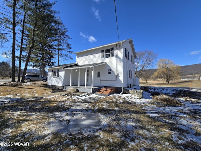 snow covered rear of property with a porch