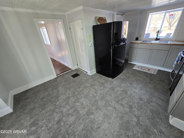 kitchen featuring black refrigerator, sink, ornamental molding, and range