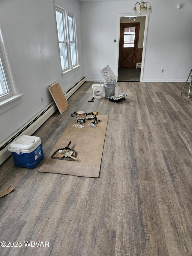 interior space featuring wood-type flooring, a wealth of natural light, and a baseboard heating unit