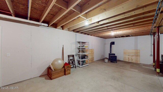 unfinished basement featuring a wood stove