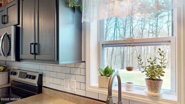 details with appliances with stainless steel finishes, gray cabinetry, and backsplash