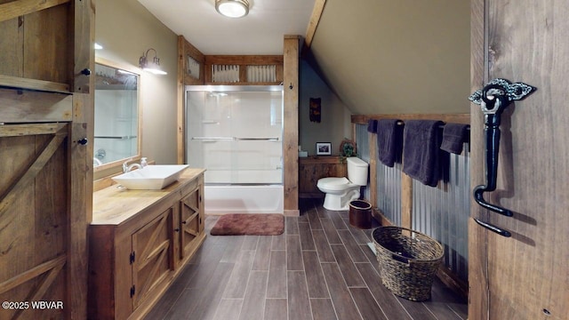 bathroom with vanity, wood finished floors, toilet, combined bath / shower with glass door, and lofted ceiling