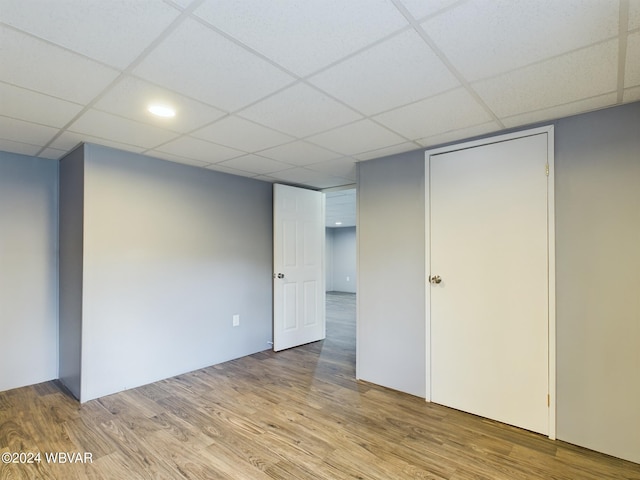 basement with a paneled ceiling and light hardwood / wood-style flooring