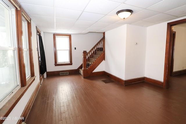 empty room featuring dark wood-type flooring and a drop ceiling