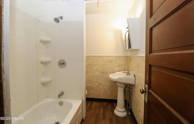 bathroom featuring hardwood / wood-style flooring, shower / bathing tub combination, and tile walls