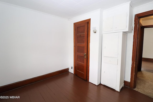 empty room with crown molding and dark hardwood / wood-style flooring