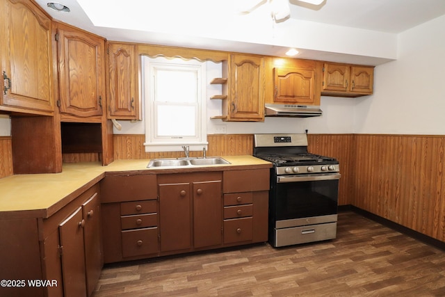 kitchen featuring dark hardwood / wood-style floors, wooden walls, sink, and stainless steel gas stove