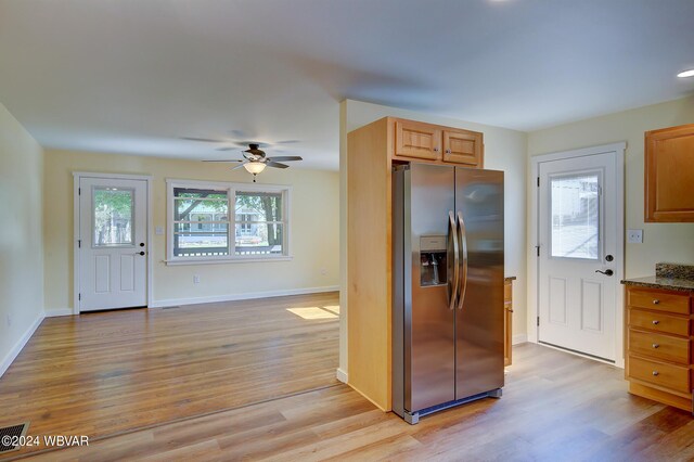 kitchen with stainless steel fridge, light hardwood / wood-style flooring, ceiling fan, and light stone counters