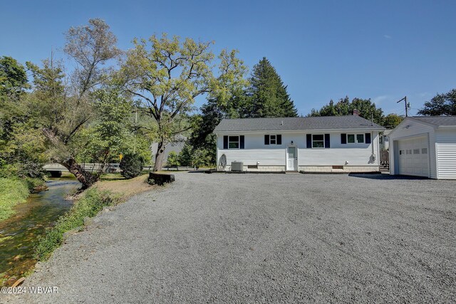 view of front of property featuring cooling unit, a garage, and an outdoor structure