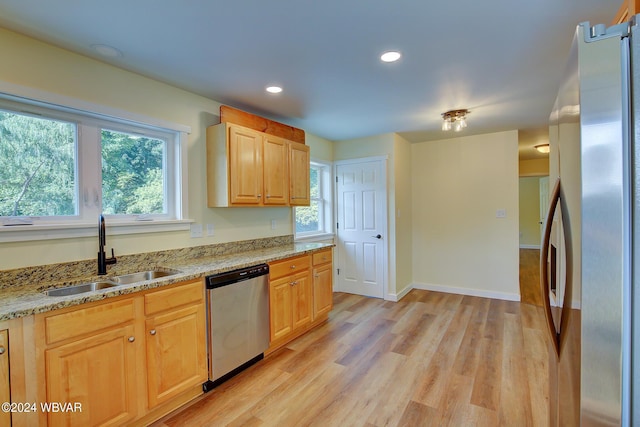 kitchen featuring sink, light brown cabinets, stainless steel appliances, light stone counters, and light hardwood / wood-style flooring