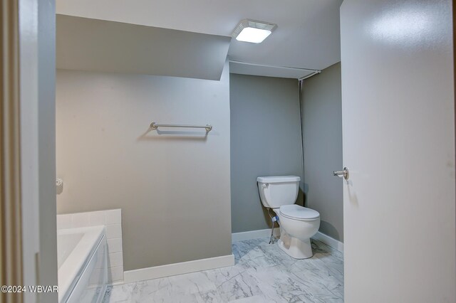 bathroom featuring a tub to relax in and toilet