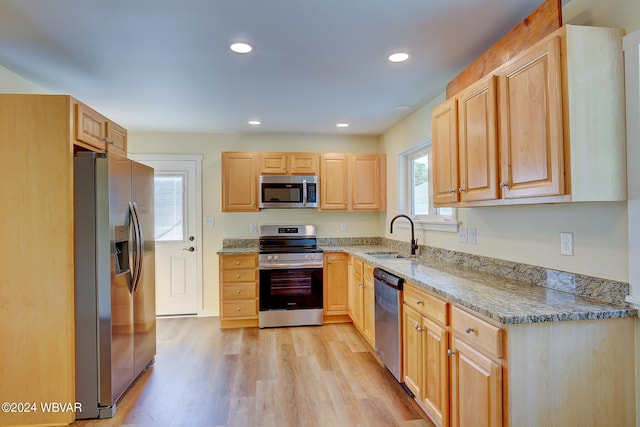 kitchen with sink, stainless steel appliances, light brown cabinets, and light hardwood / wood-style flooring