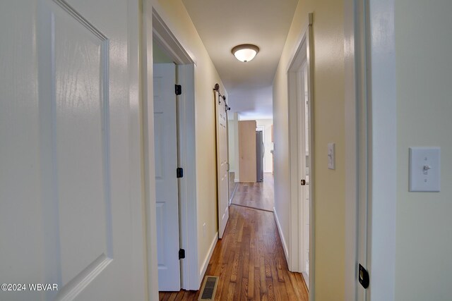 hall featuring a barn door and wood-type flooring